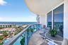 Curved balcony with glass railing, marble flooring, and sliding glass doors