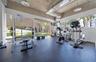 Fitness area featuring exposed concrete ceilings, expansive floor-to-ceiling windows, rubberized flooring, and industrial-style pendant lighting