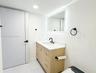 Light-finish wood vanity with a white countertop, rectangular undermount sink, integrated LED-lit mirror, and matte black fixtures