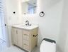 Light wood-finish vanity with a white countertop, rectangular undermount sink, matte black faucet, and an integrated backlit mirror