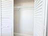 Storage closet featuring white louvered bifold doors and an integrated shelving rod