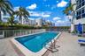 Swimming pool with a paved deck, metal railings, and perimeter hedging