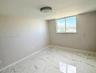 Large-format stone-style flooring with veining, neutral wall finish, and a sliding window