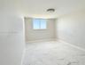 Neutral interior featuring stone-finish tile flooring, a sliding window, and a flush-mount ceiling fixture