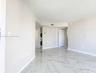 Neutral-toned interior space featuring polished stone-finish flooring with veining, white louvered closet doors, and a stacked laundry appliance set