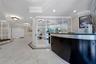 Lobby featuring polished stone flooring, custom grid-patterned glass partitioning, crown molding, recessed lighting, and a built-in reception desk wit