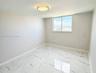 Large-format tile flooring with veined detailing, neutral wall tones, flush-mount ceiling light fixture, and a single sliding window