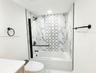 Bathtub with floor-to-ceiling marbled wall tile and decorative geometric tile inlay, complemented by matte black fixtures including a wall-mounted tow
