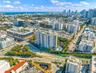 Aerial perspective of a high-rise residential building featuring an outdoor swimming pool, landscaped grounds, and proximity to the coastline