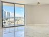 Large-format polished tile flooring, floor-to-ceiling sliding glass doors, and a private balcony with metal railing