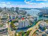Aerial perspective of mid-rise residential building featuring a rooftop pool, private surface parking, and proximity to the waterfront