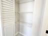 Storage closet featuring white louvered double doors and interior white wire shelving