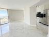 Large-format tiled flooring with veined detailing, white cabinetry, stainless steel appliances, and sliding glass door access to an exterior balcony
