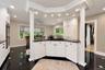 Kitchen featuring white shaker-style cabinetry, black stone countertops, integrated gas cooktop, recessed lighting, and decorative columns