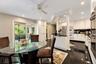 Kitchen featuring white cabinetry, black countertops, recessed lighting, a decorative architectural column, and polished dark tile flooring