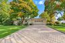 Single-story brick exterior featuring a patterned paver driveway, attached two-car garage, and established landscaping