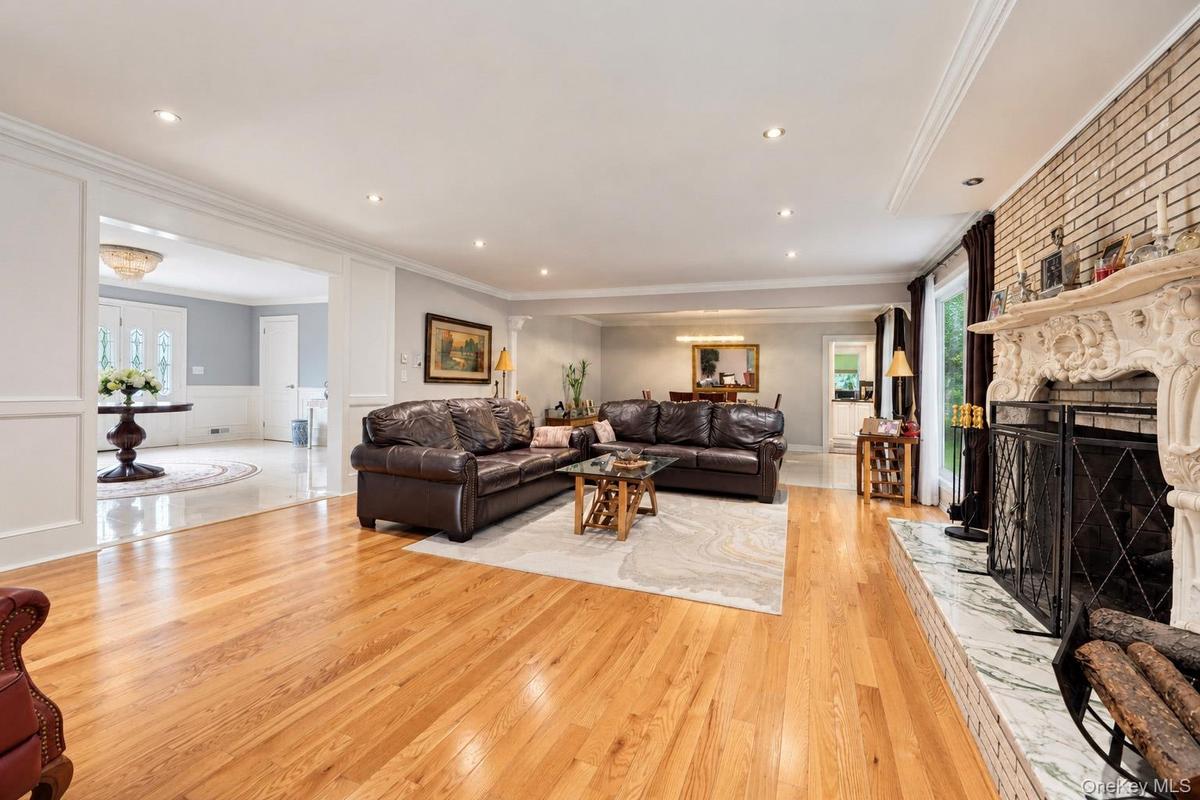 Living area featuring wood-finish flooring, an ornate fireplace mantel, stone hearth, recessed lighting, and crown molding