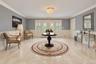 Foyer featuring large-format tile flooring, double doors with decorative glass inserts, crown molding, and wainscoting, accented by a tiered crystal-s