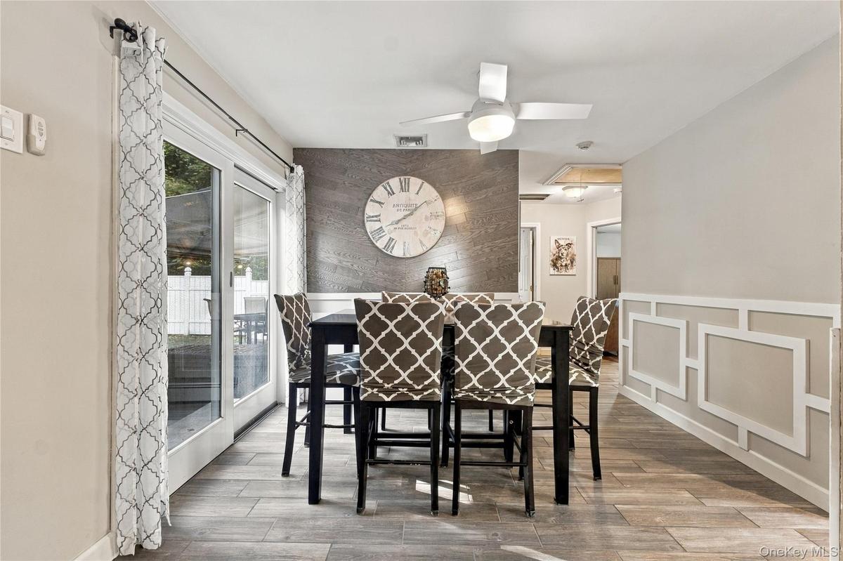 Dining area with ceramic tile foor, wainscoting, sliders to patio and ceiling fan