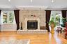 Light-toned brick fireplace with an ornate carved mantel and stone hearth, wood-finish flooring, recessed lighting, and glass paneled doors