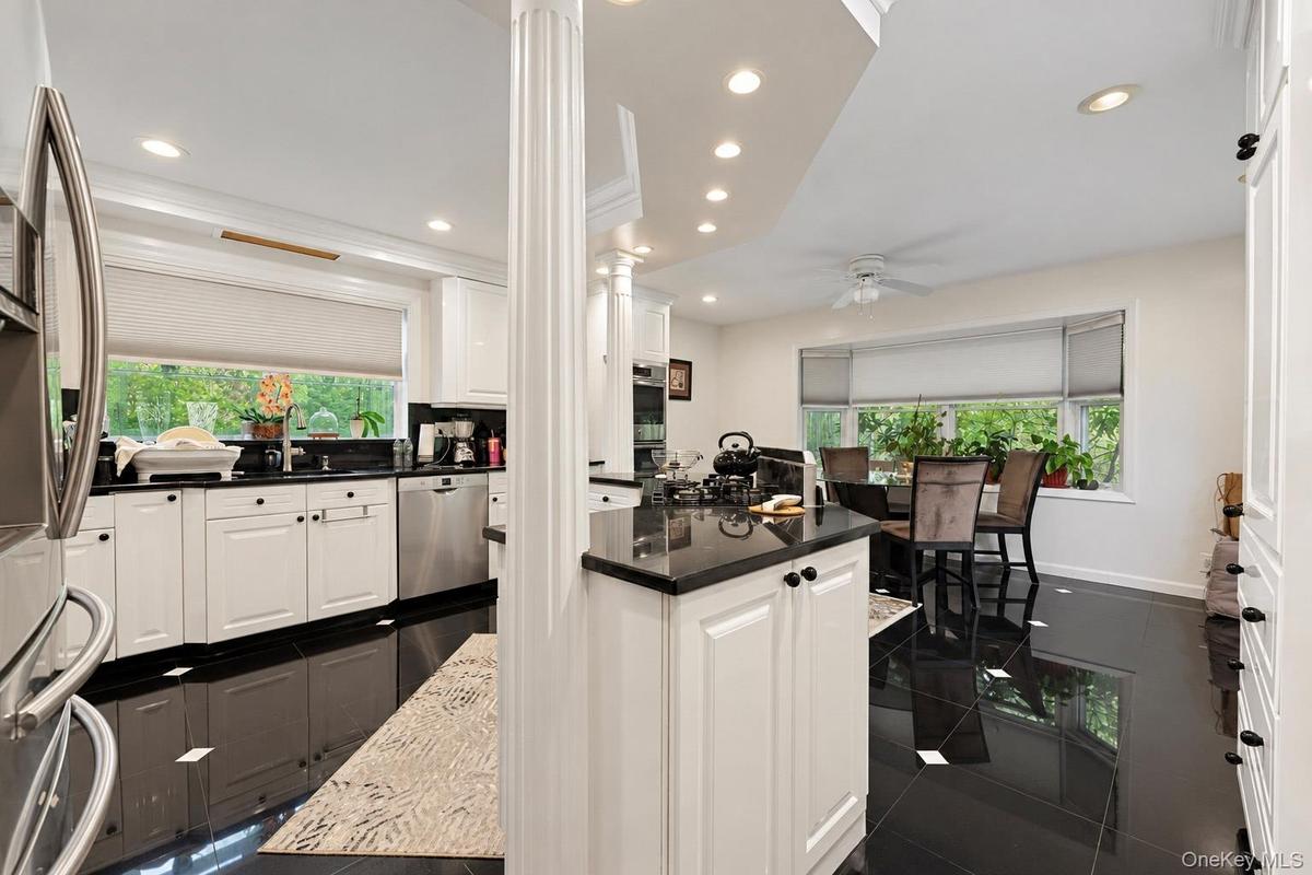 Kitchen featuring white cabinetry, dark stone countertops, stainless steel appliances, recessed lighting, and black tile flooring