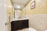 Dark-finish vanity featuring a stone-surface countertop, gold-toned faucet hardware, a wall-to-wall mirror, and textured tile wall accents