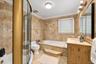 Bathroom featuring floor-to-ceiling stone tile, a glass-enclosed corner shower, a built-in soaking tub with a stone surround, and an integrated stone-