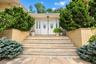 Double front doors with oval decorative glass inserts, brick-accented stone steps, and raised brick planters