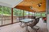 Screened in porch with vaulted ceiling, outdoor dining area, and ceiling fan