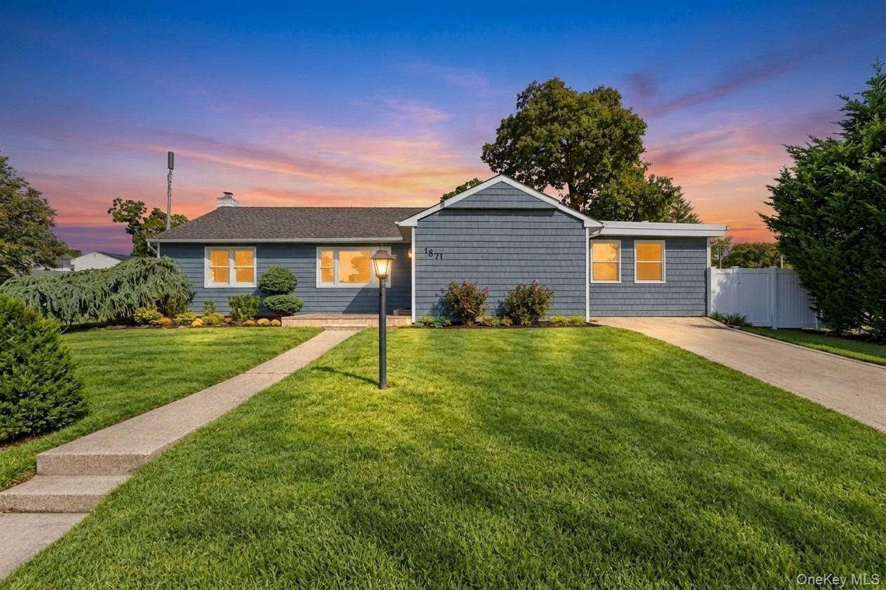 Ranch-style exterior featuring blue shake siding, architectural shingle roof, concrete driveway, front walkway, and mature landscaping