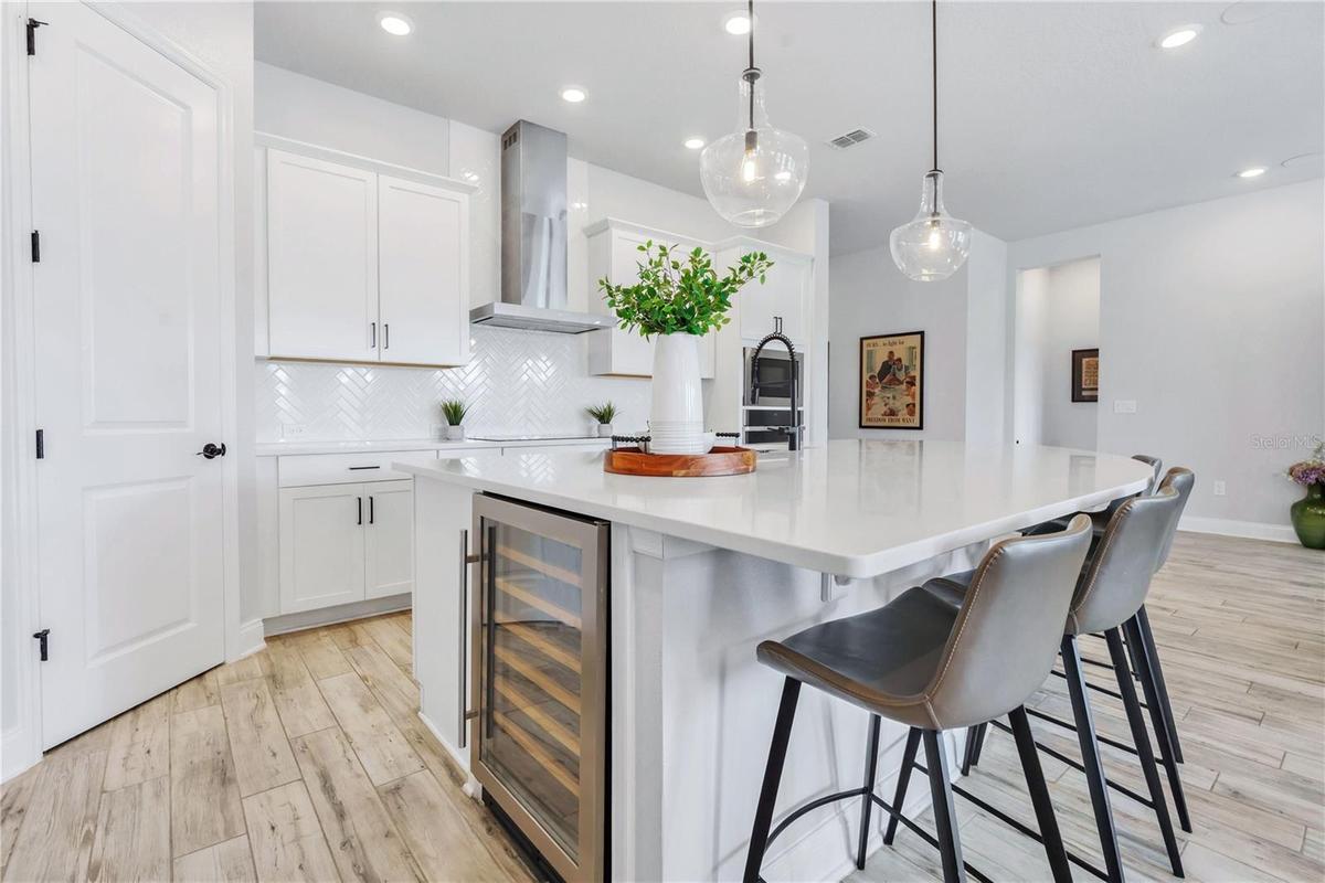 Quartz island with built in wine refrigerator, matte black hardware, and counter seating. A true centerpiece for hosting.