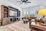 Spacious family room with a custom entertainment wall and wood look plank tile, flowing into the kitchen and dining area.