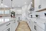 White 42 inch cabinetry, stainless range hood, and herringbone backsplash. Abundant storage plus a walk in pantry.