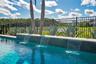 Spa spillover into the heated salt water pool with a fenced backyard and tropical landscaping.