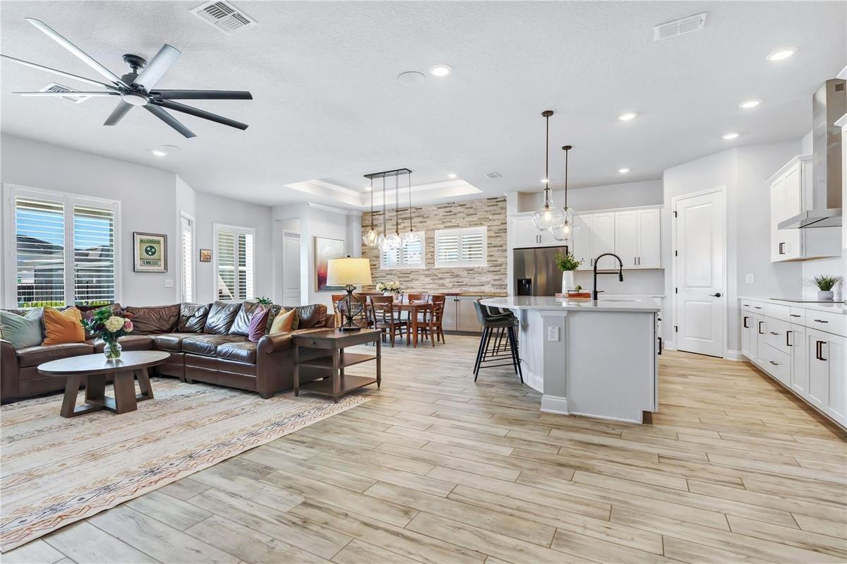 Bright great room open to the kitchen with high ceilings, ceiling fan, and plantation shutters. Easy everyday living in Laureate Park, Lake Nona.
