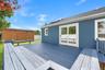 Exterior wood deck featuring integrated bench seating, horizontal siding, sliding glass doors, and a detached wooden storage structure