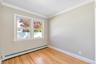 Neutral-toned interior space featuring wood-finish flooring, double-pane windows, and crown molding