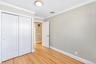 Room featuring wood-finish flooring, white panel doors, dual sliding closet doors, and crown molding