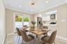 Dining area featuring stone-finish tile flooring, crown molding, modern geometric light fixture, and sliding glass doors with backyard access