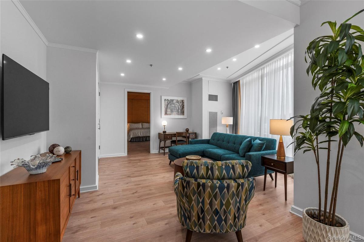 Living room with crown molding, light wood finished floors, recessed lighting, visible vents, and baseboards