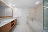 Bathroom featuring tile walls, double vanity, a garden tub, and a wainscoted wall