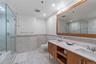 Bathroom with tile walls, visible vents, a sink, and a shower stall