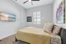 Secondary bedroom with ceiling fan, carpet, and natural light.