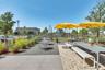 Outdoor gathering space with shaded tables, ideal for relaxing and meeting neighbors in Laureate Park.