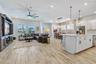 Open floor plan connecting the great room, kitchen, and dining area. Wood look plank tile, crown moulding, and natural light throughout this one story