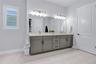 Primary bath vanity with dual sinks, quartz counters, framed mirrors, and modern lighting.