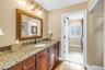 The primary bathroom features high-quality custom solid wood cabinetry, granite countertops, and elegant lighting and bath fixtures.