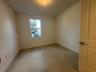Kitchen featuring wood-finish cabinetry, quartz countertops, a stone-tile backsplash, stainless steel appliances, and large-format tile flooring