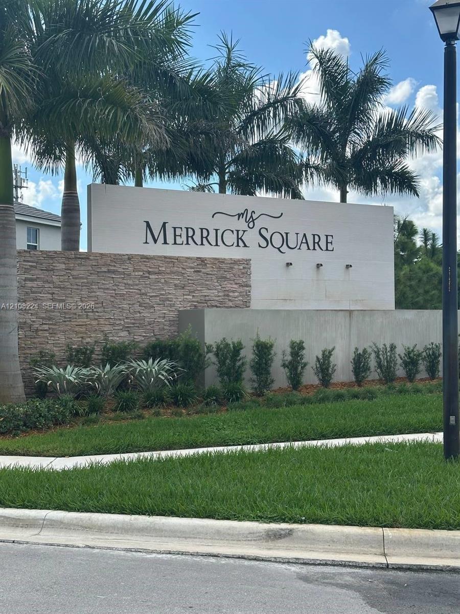 Monument signage featuring stacked stone accents, smooth concrete walls, and mature palm landscaping