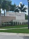 Monument signage featuring stacked stone accents, smooth concrete walls, and mature palm landscaping